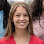 Multiethnic gen z group of people smiling looking at the camera - closeup on a beautiful candid cheerful girl with light brown straight hair - unity, diversity and integration concept